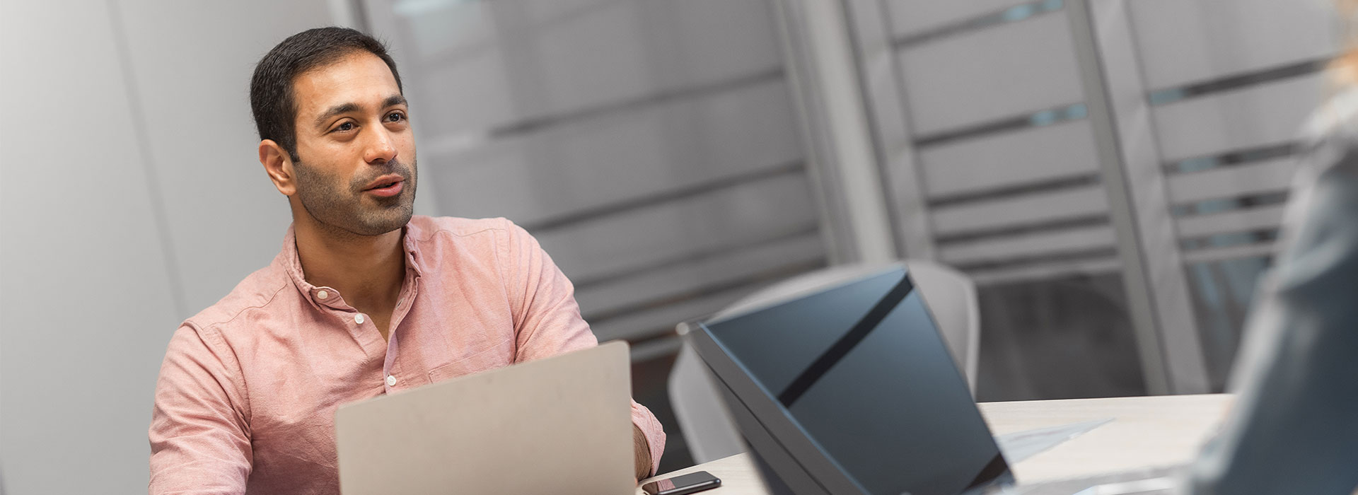 Man-achter-laptop-in-overleg-met-iemand