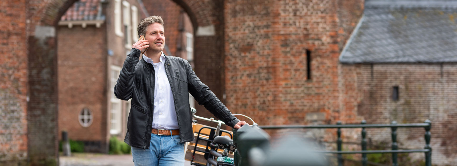 Man-buiten-bellend-leunend-op-reling